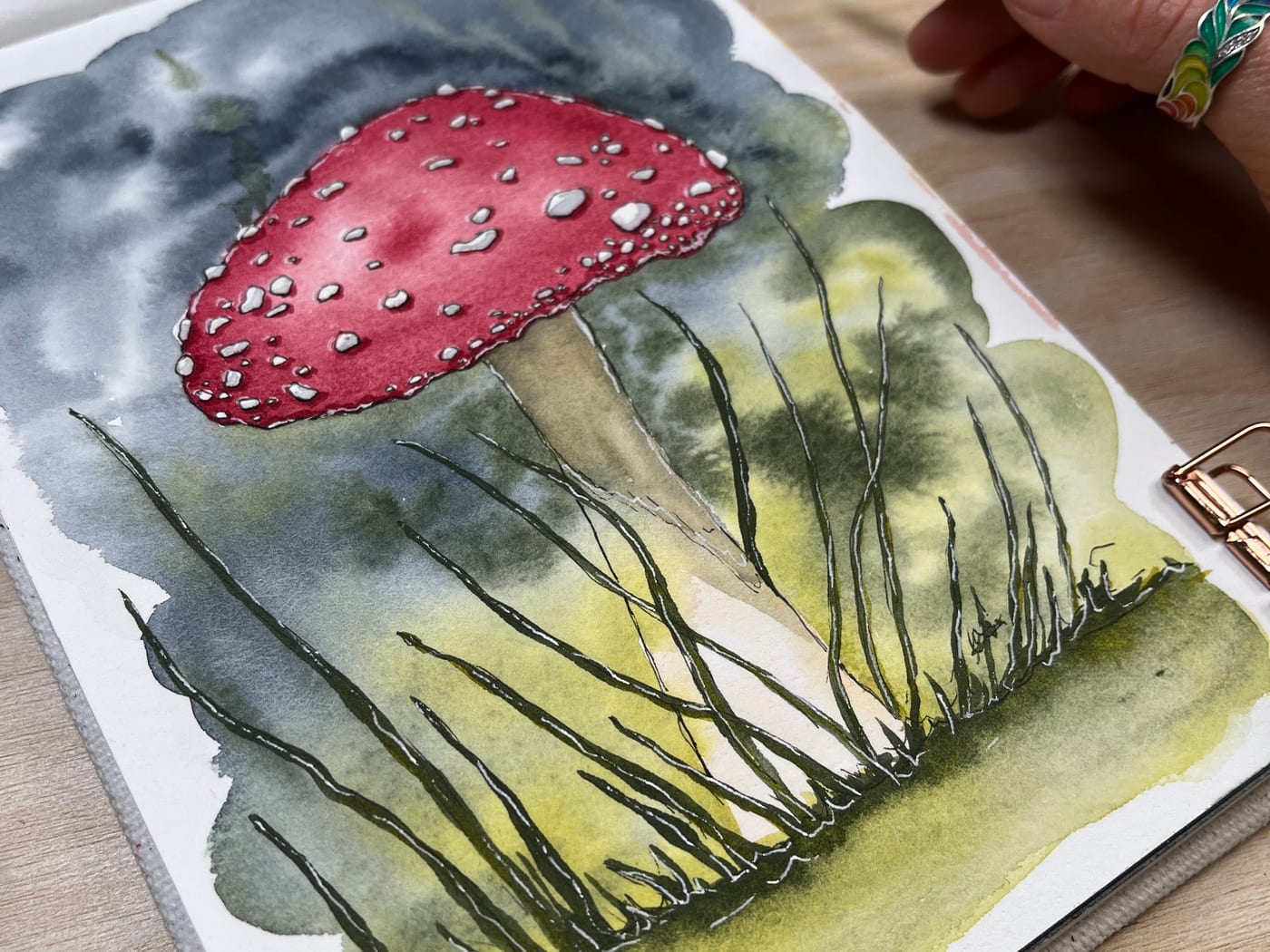 Watercolour and ink painting of a red toadstool in the grass