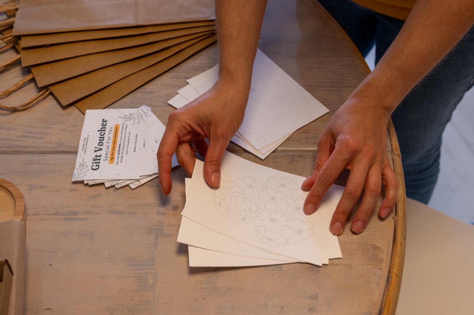 Gabriela laying out printed templates on watercolour paper next to gift vouchers and paper bags