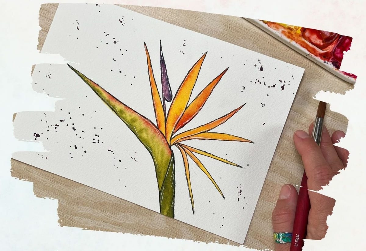 A hand painting a bird of paradise flower in ink and watercolor on a greeting card